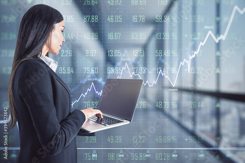 Businesswoman working with laptop in office on background of financial chart, double exposure