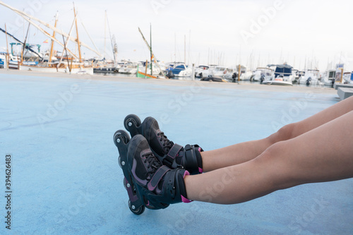 Beautiful young woman legs in black roller skates, with blurred port background.Sport lifestyle concept.