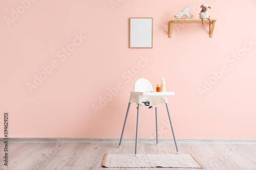 Modern interior with baby highchair on color background