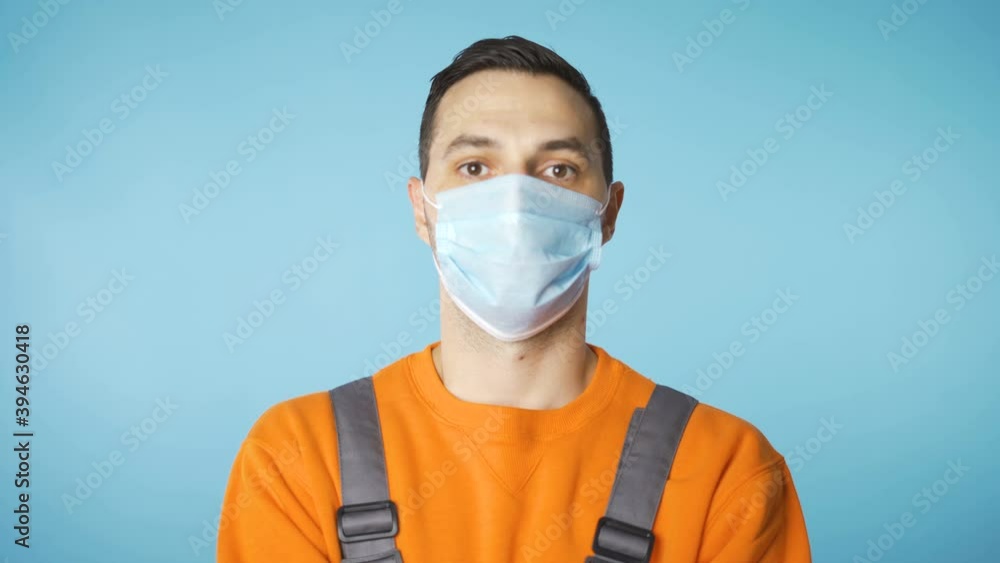 Serious looking man in industrial working clothes and face mask walking towards camera with hands on chest Serious looking man in industrial working clothes and face mask walking towards camera with hands on chest