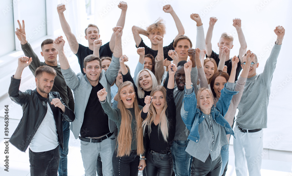 large group of happy young people with hands up