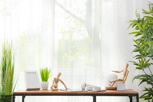 Wooden mannequins with modern devices on table in room