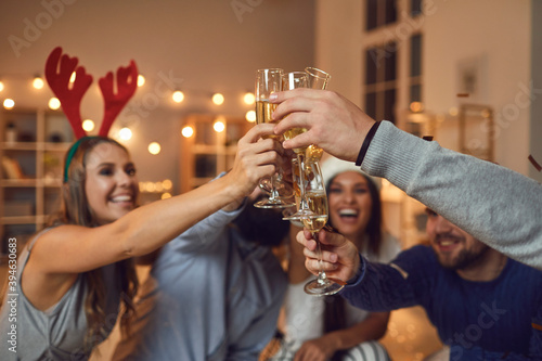 Friends lift up with glasses of champagne and make toasts, wishing each other a Happy New Year.