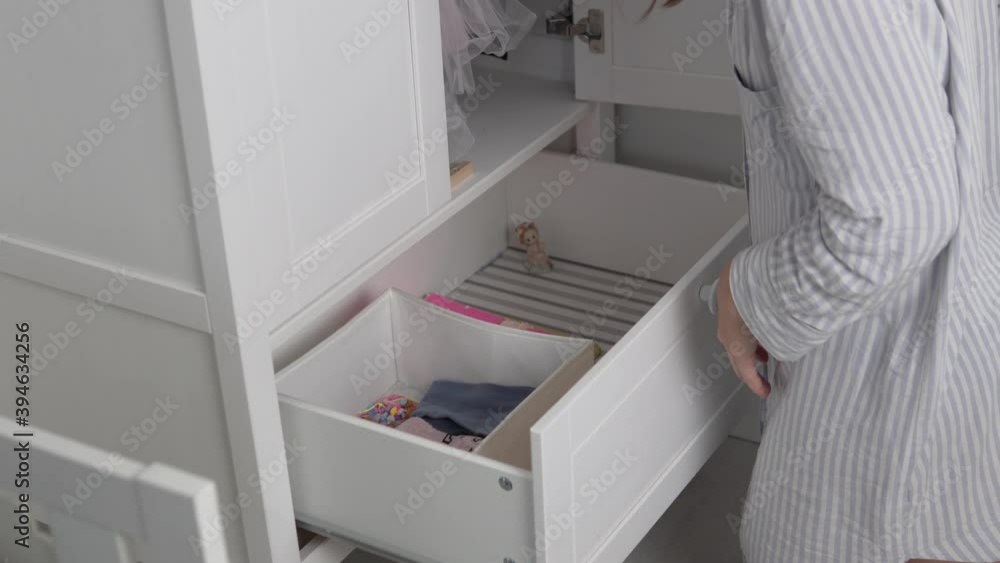 Mom puts things neatly in the closet of her little daughter, a woman is a housewife cleaning the children's room. Mom puts things neatly in the closet of her little daughter, a woman is a housewife cleaning the children's room.