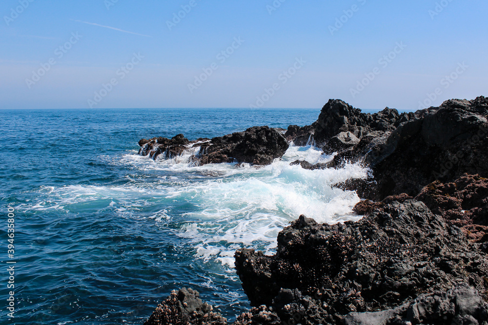Blue ocean waves with rocks on the beach