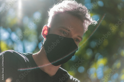 young man with white hair wearing a black face mask in forest, during corona time