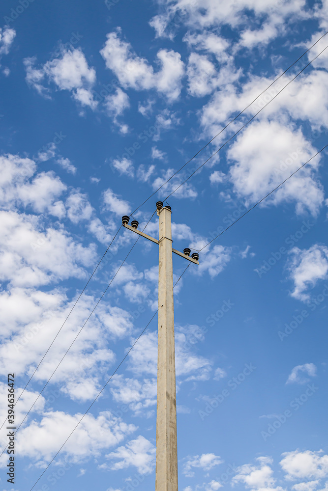 Electric concrete pole with wires. Background sky with light clouds. Metal constructions. Ceramic insulators. Electric concrete pole with wires. Background sky with light clouds. Metal constructions. Ceramic insulators.