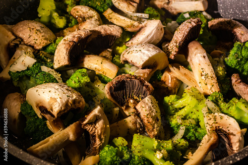 White champignons, onion and green broccoli fry on pan or wok. Hot delicious vegetarian dinner.