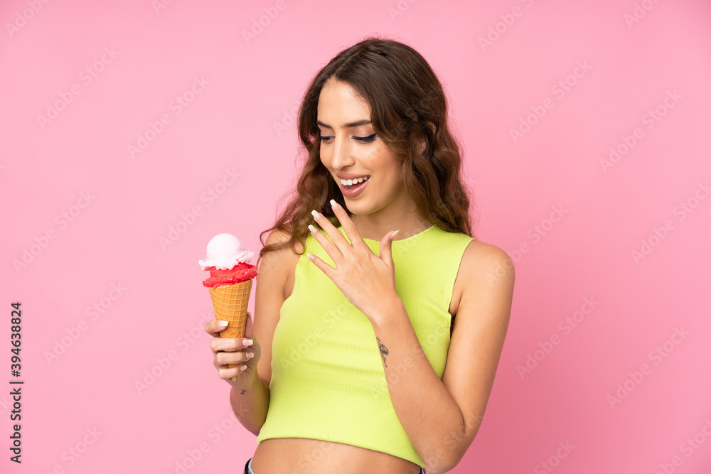 Young woman holding a cornet ice cream over isolated on a pink background with surprise and shocked facial expression Young woman holding a cornet ice cream over isolated on a pink background with surprise and shocked facial expression