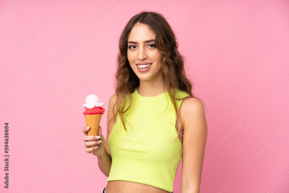 Young woman holding a cornet ice cream over isolated on a pink background smiling a lot Young woman holding a cornet ice cream over isolated on a pink background smiling a lot
