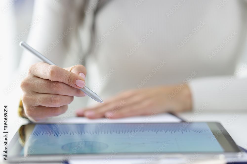 Female hand holds stylus over included tablet with business records. Business applications concept Female hand holds stylus over included tablet with business records. Business applications concept