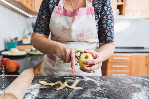 Young housewife peels apple for applie pie. photo