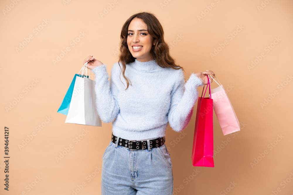 Young woman over isolated background holding shopping bags and smiling
