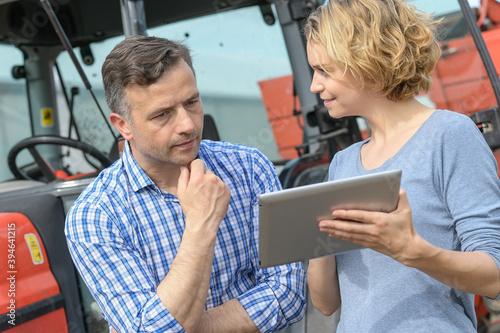 Couple of Farmer analyses the harvesting data next to the tractor
