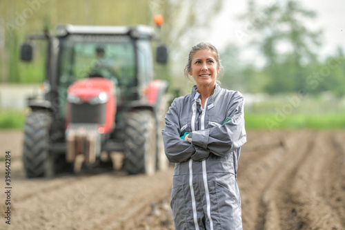 Portrait of a woman farmer standing in the field in front of a tractor