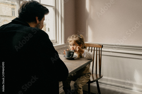 Father and daughter sitting at a table drinking hot chocolate