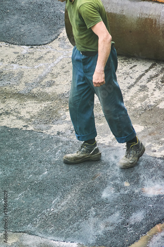 worker man walks on new smoking asphalt