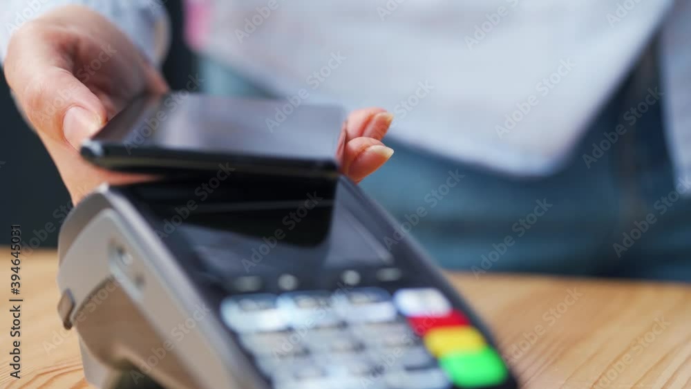 Contactless payment with smartphone. Wireless payment concept. Close-up, woman using smartphone cashless wallet NFC technology to pay order on bank terminal. Contactless payment with smartphone. Wireless payment concept. Close-up, woman using smartphone cashless wallet NFC technology to pay order on bank terminal.