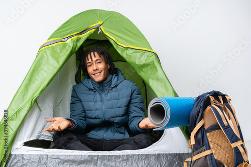Young african american man inside a camping green tent smiling