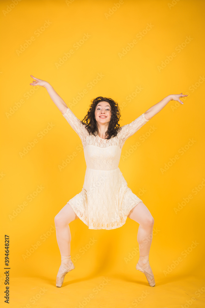 Graceful classic ballerina dancing on yellow studio