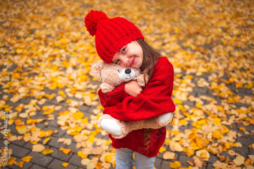 Happy little girl playing with his teddy bear toy in autumnal park