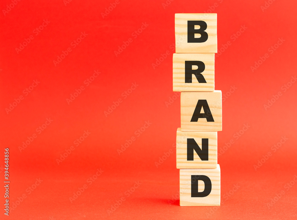 Wooden cubes with word BRAND. Wooden cubes on a red background. Free space on the left. Wooden cubes with word BRAND. Wooden cubes on a red background. Free space on the left.