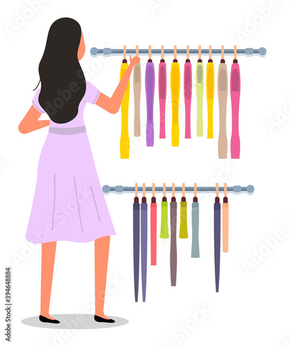 The girl is choosing colored garment on hangers. The young fashion woman in dress isolated on white background. Buyer is selecting clothes in a store. Shopper during the sale. Rack with clothing items