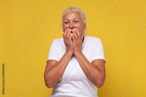 Senior woman giggles covering her mouth with hand photo