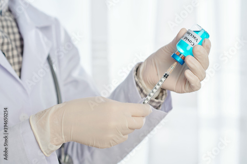 Close-up image of doctor with syringe taking vaccine against covid-19 from glass bottle photo