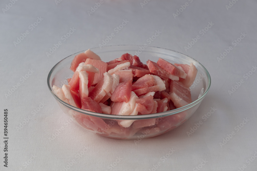 Pieces of fresh, raw pork are cut and placed on a plate. Meat as an ingredient Pieces of fresh, raw pork are cut and placed on a plate. Meat as an ingredient