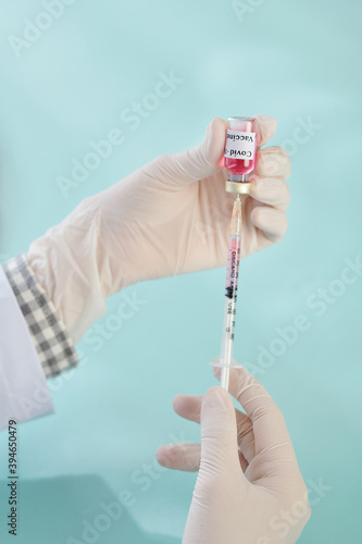 Hands of general practitioner holding syringe and vial with vaccine against coronavirus photo