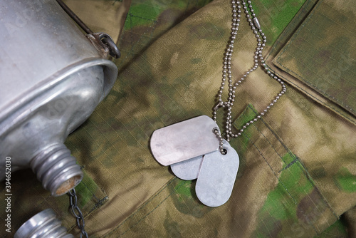 Fotografi a soldier's water bottle lies on camouflage with soldier badge on a chain