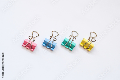 Colored iron paper clips. paper clips with many unique pastel color variants isolated on a white background, Binder clip is a simple device for binding sheets of paper together, metal clips in chaos