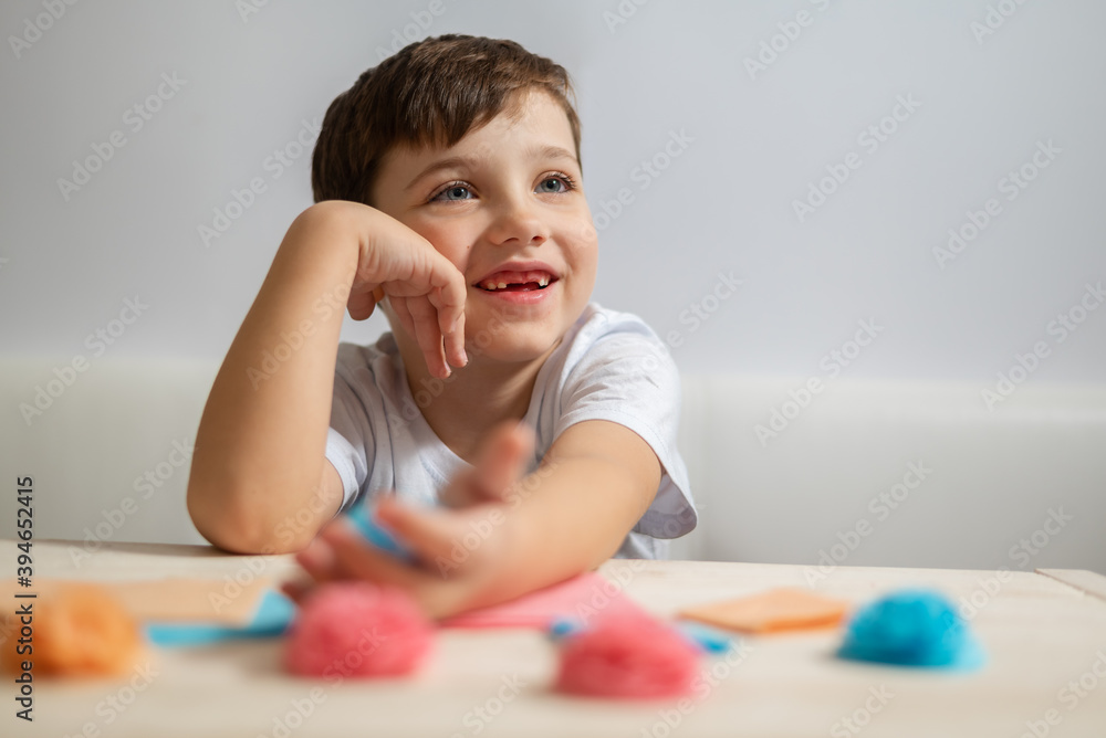 Happy little kid boy sitting at the table and listening lesson teacher and crafting flowers with paper Happy little kid boy sitting at the table and listening lesson teacher and crafting flowers with paper