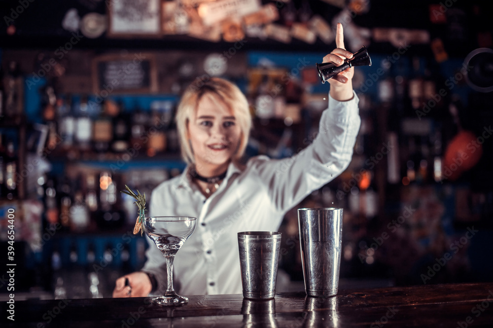 Girl bartender mixes a cocktail at the bar