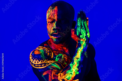 afro american man with UV body art posing in studio
