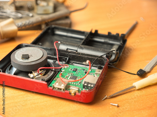Close-up of a faulty radio receiver and a tool for repairing it. Soldering iron, screwdriver, motherboard, equipment repair.Selective focus, shallow depth of field