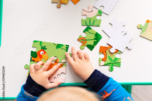 Baby boy solving jigsaw puzzle on the desk
