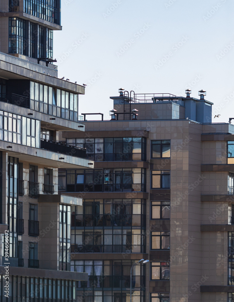 Modern residential buildings. Sunny day. Reflections in windows. Combination of cold blue and warm orange hues.  