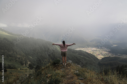 girl tourist, standing on the top of the mountain, arms are spread apart