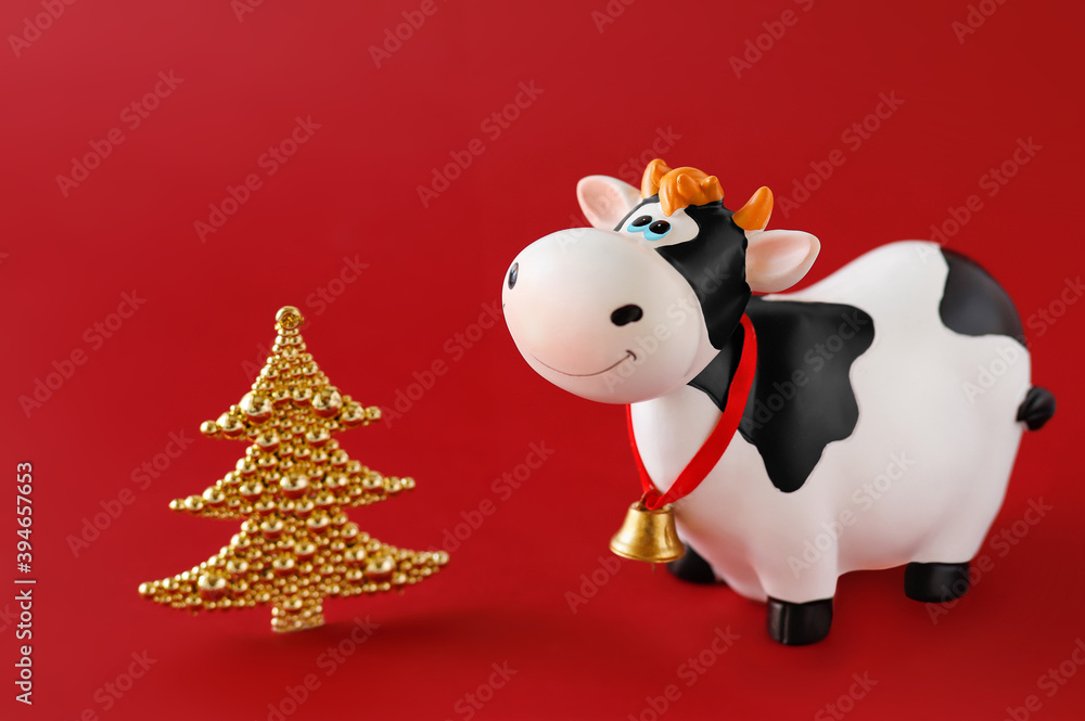 Toy bull with a miniature decorative Christmas tree on a red background. Symbol of the Chinese New year 2021. New year's mood. Toy bull with a miniature decorative Christmas tree on a red background. Symbol of the Chinese New year 2021. New year's mood.
