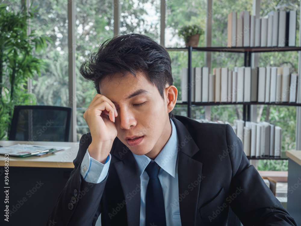 Stressed businessman. Young Asian business man in suit feeling down and tired.