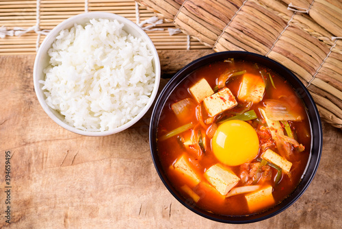 Korean food, Kimchi soup with fofu and egg eating with cooked rice on wooden background