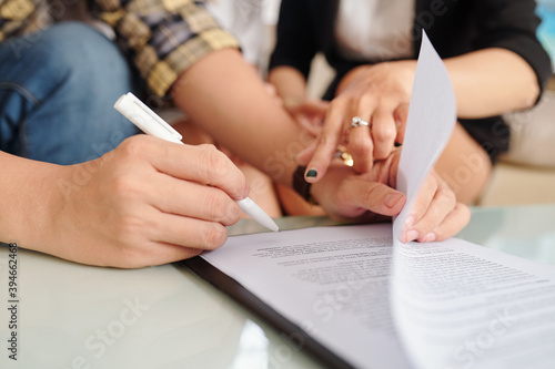 Close-up image of real estate manager showing client where to sign contract