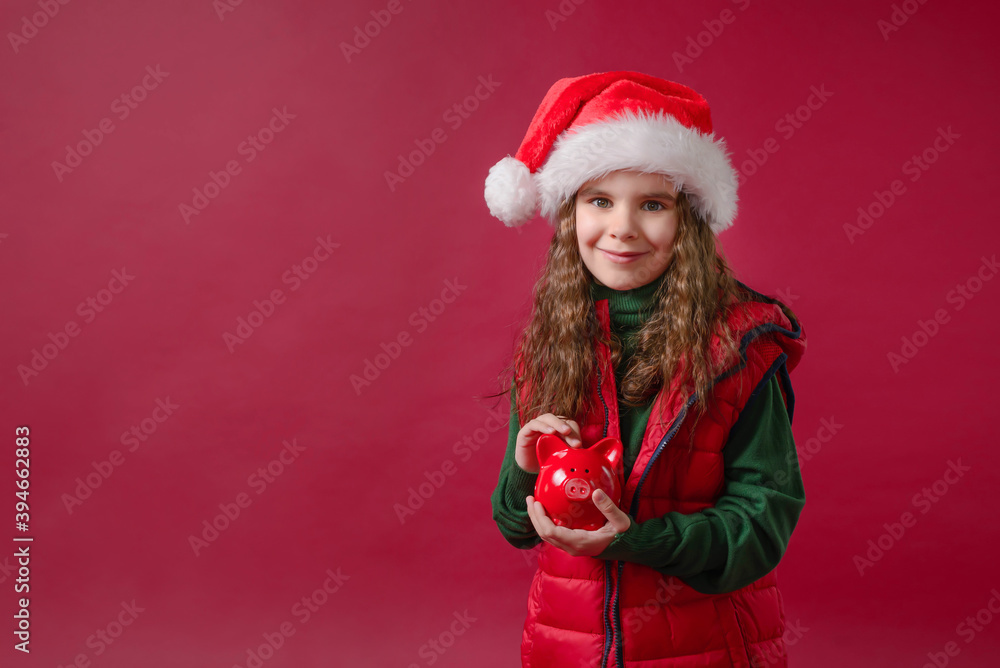 Cute girl kid holding a red piggy Bank or boar on a red background. Holidays, savings, traditions concept. Cute girl kid holding a red piggy Bank or boar on a red background. Holidays, savings, traditions concept.