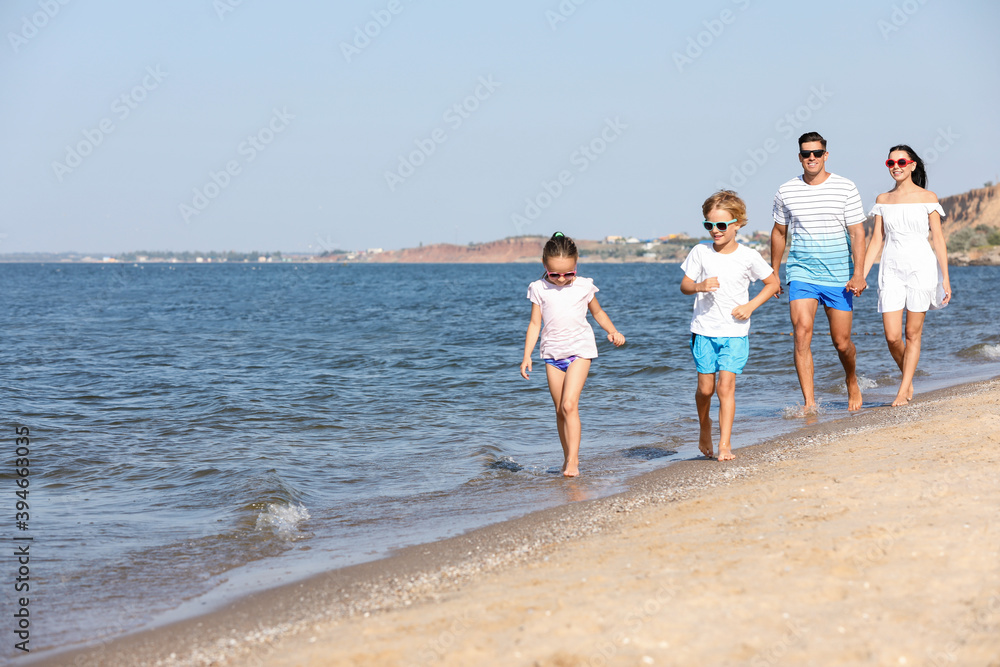 Happy family walking on sandy beach near sea. Summer holidays Happy family walking on sandy beach near sea. Summer holidays