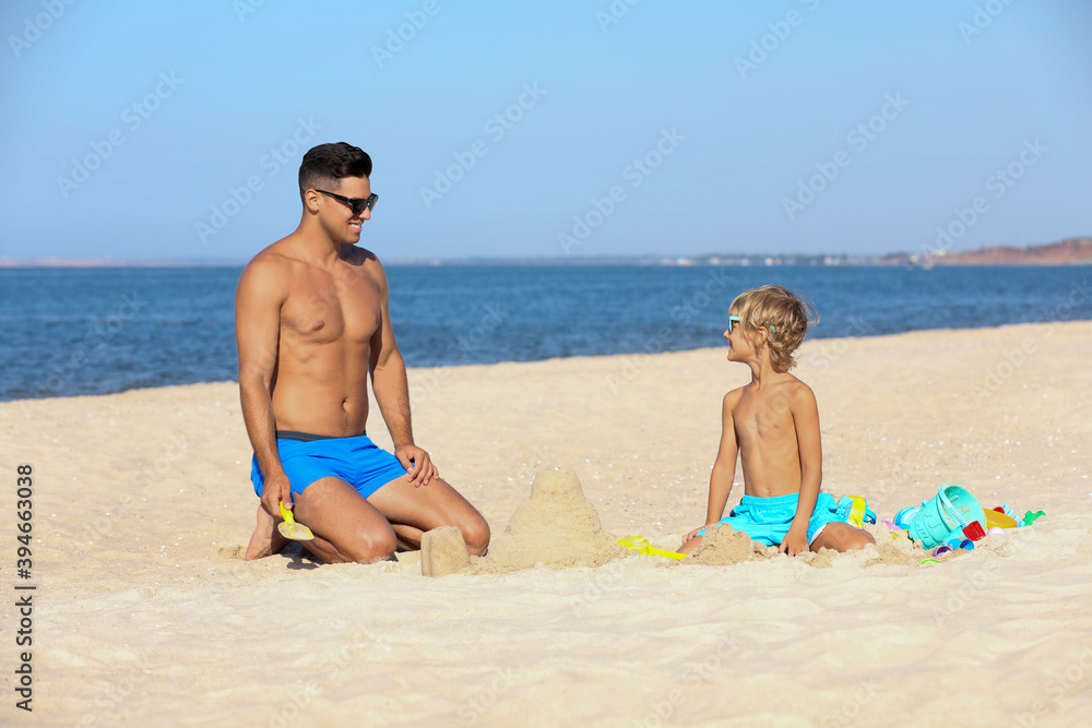 Father and son playing on sandy beach near sea. Summer holidays with family Father and son playing on sandy beach near sea. Summer holidays with family