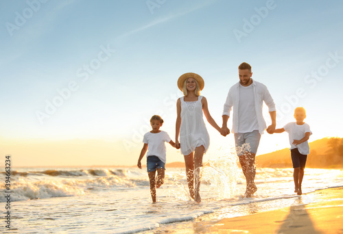 Happy family on sandy beach near sea at sunset