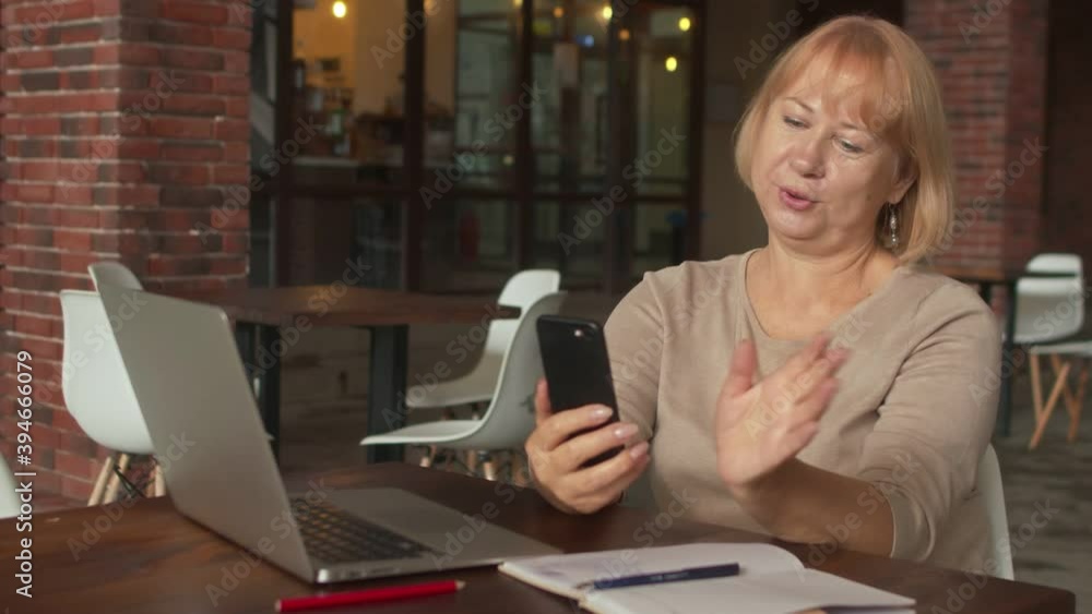 Positive Senior woman having a video call in cafe Positive Senior woman having a video call in cafe