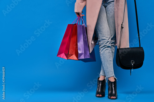 .Girl holding shopping bags on a blue background, close up image